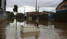 Un habitant utilise un réfrigérateur endommagé comme embarcation pour transporter des provisions dans une rue inondée de Porto Alegre, dans l'État de Rio Grande do Sul, au Brésil, le 26 mai 2024, pendant des inondations historiques dans le pays ( AFP / Anselmo Cunha )