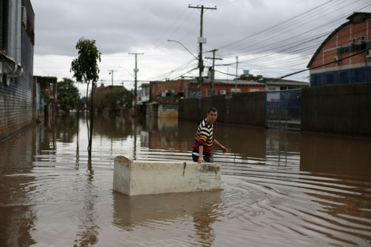 Un habitant utilise un réfrigérateur endommagé comme embarcation pour transporter des provisions dans une rue inondée de Porto Alegre, dans l'État de Rio Grande do Sul, au Brésil, le 26 mai 2024, pendant des inondations historiques dans le pays ( AFP / Anselmo Cunha )