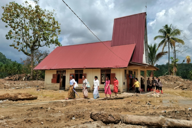 Des villageoisquittent l'église protestante d'Angkola après la messe de Noël, dans le village d'Aek Ngadol, le 25 décembre 2025, dans la province de Sumatra touchée par des inondations et glissements de terrain meurtriers, en Indonésie ( AFP / AMROE )