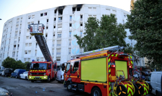 Des véhicules de pompiers stationnés devant un bâtiment où un incendie criminel a fait sept morts dans la nuit, le 18 juillet 2024 à Nice ( AFP / Valery HACHE )