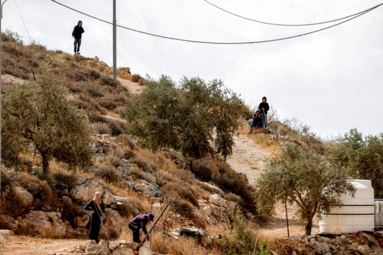 De jeunes colons israéliens surplombent des Palestiniens, en périphérie du village de d'Al-Mughayyir, en Cisjordanie, le 29 septembre 2026 ( AFP / Zain JAAFAR )