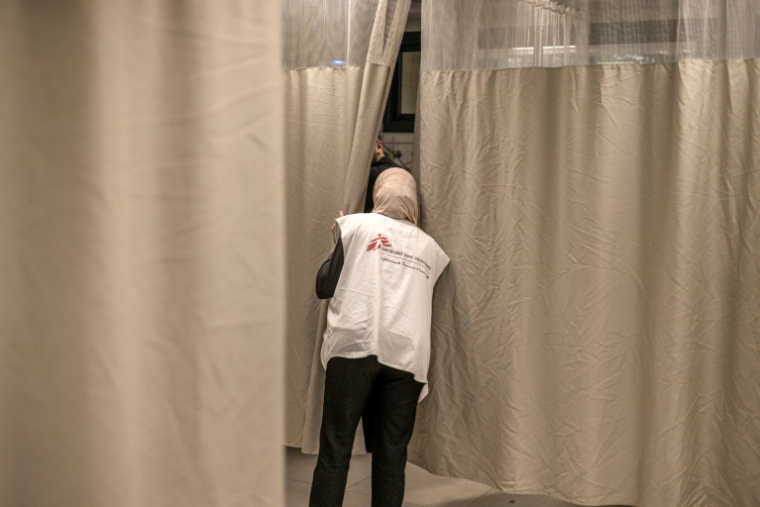 Une membre du personnel de l'ONG Médecins sans frontières» examine un patient derrière un rideau au service des urgences de l'hôpital gouvernemental de Jénine, en Cisjordanie occupée, le 24 janvier 2024 ( AFP / MARCO LONGARI )