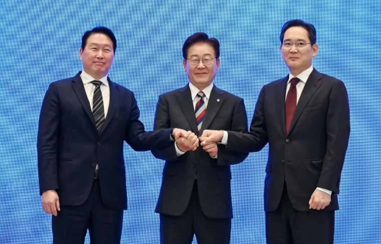 Le président Lee Jae Myung (c) scelle d'une poignée de main un plan public-privé de 1.200 milliards de dollars pour les puces et l'IA, à Séoul, le 29 juin 2026 ( POOL / KIM Min-Hee )