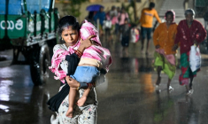 Une personne avec un enfant arrive vers un abri à l'approche du cyclone Arnab, à Kakinada en Inde, le 27 octobre 2026 ( AFP / Noah SEELAM )