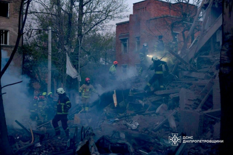Photo prise et diffusée par le Service d'État des situations d'urgence de l'Ukraine, le 25 avril 2026, montrant des secouristes dans les décombres d'un immeuble résidentiel après une attaque russe à Dnipro, dans le centre-est du pays  ( State Emergency Service of Ukraine / Handout )