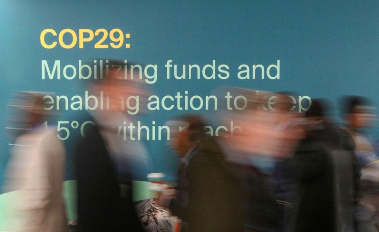 Des participants passent devant un panneau lors de la COP29 à Bakou, en Azerbaïdjan