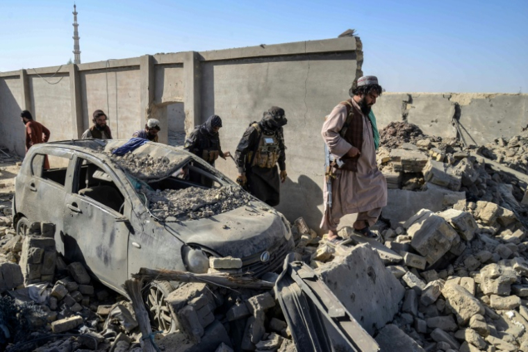 Des membres des forces de sécurité talibanes passent devant une voiture endommagée dans le district de Spin Boldak, dans la province de Kandahar, le 16 octobre 2025, au lendemain d'affrontements à la frontière entre l'Afghanistan et le Pakistan ( AFP / Sanaullah SEIAM )