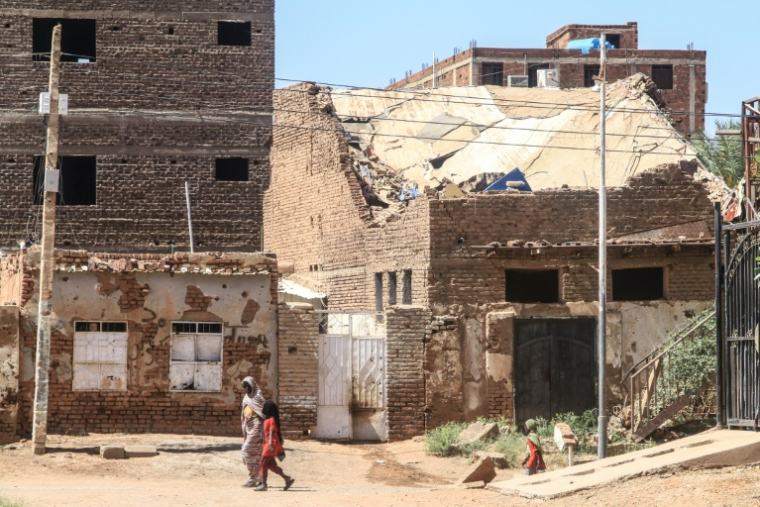 Une femme et un enfant passent devant un bâtiment endommagé dans la capitale soudanaise Khartoum le 15 avril 2026 ( AFP / Ebrahim Hamid )