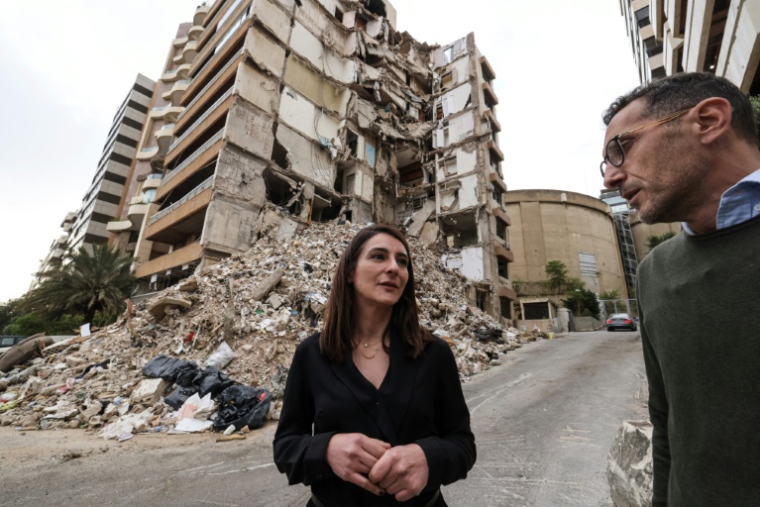 Ghida Krisht (gauche) et Wael Sabbagh (droite), qui ont perdu des proches dans la destruction d'un immeuble par une frappe israélienne, se tiennent devant le bâtiment, dans le quartier de Tallet el-Khayat, à Beyrouth, le 18 mai 2026 ( AFP / Anwar AMRO )