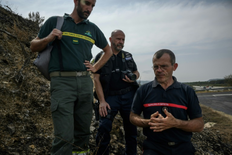 (g-d) Stéphane Paoli, technicien de l'ONF, le gendarmer Emmanuel Guinard et Jean-Paul Baylac, chef du service des incendies de forêt du Service d'incendie et de secours de l'Aude, inspectent une zone touchée par un récent incendie de forêt, à Luc-sur-Orbieu, près de Narbonne, le 19 août 2025 ( AFP / Ed JONES )