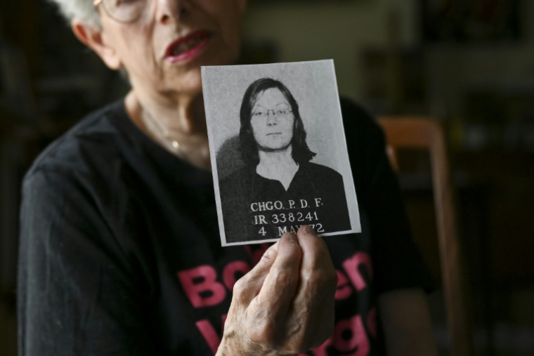 Abby Pariser, ancienne membre du réseau clandestin "Jane" montre une copie d'une photo d'identité judiciaire de Sheila Smith, une autre "Jane" arrêtée à ses côtés en 1972, le 5 juin 2025 depuis Huntington dans l'Etat américain de New York ( AFP / ANGELA WEISS )