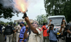Un policier tire des grenades lacrymogènes pour disperser des militants du "Parti du peuple des cafards" (CJP) lors d'une manifestation réclamant la démission du ministre de l'Éducation, Dharmendra Pradhan, en raison de fraudes présumées aux examens universitaires, le 20 juillet 2026 à New Delhi, en Inde ( AFP / Sajjad HUSSAIN )