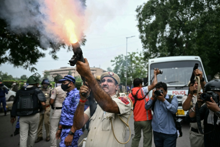 Un policier tire des grenades lacrymogènes pour disperser des militants du "Parti du peuple des cafards" (CJP) lors d'une manifestation réclamant la démission du ministre de l'Éducation, Dharmendra Pradhan, en raison de fraudes présumées aux examens universitaires, le 20 juillet 2026 à New Delhi, en Inde ( AFP / Sajjad HUSSAIN )