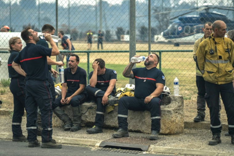 Des pompiers se reposent dans un poste de commandement de campagne installé à Saint-Laurent-de-la-Cabrerisse, le 6 août 2025 ( AFP / Idriss BIGOU-GILLES )