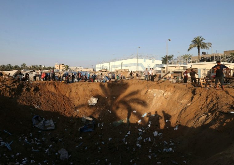 Des Palestiniens déplacés regardent un immense cratère à la suite d'une frappe aérienne israélienne qui a visé l'entrepôt de fournitures médicales de l'hôpital d'Al-Aqsa, à Deir al-Balah, dans le centre de la bande de Gaza, le 1er août 2026 ( AFP / Eyad Baba )