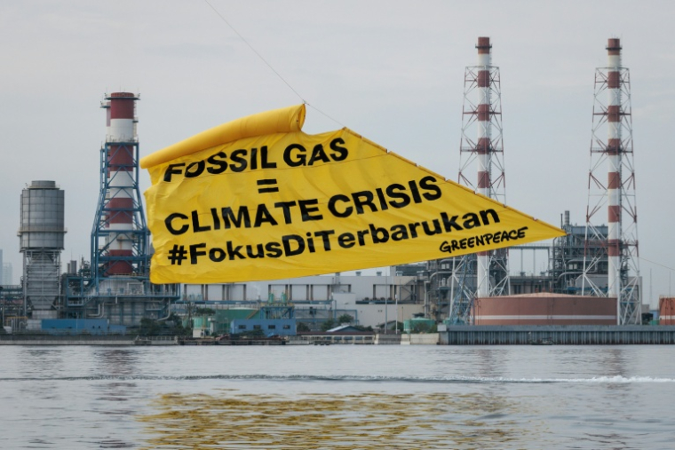 Des militants de Greenpeace déploient une banderole contre les énergies fossiles, devant une centrale électrique à gaz, à Jakarta, le 18 novembre 2025 ( AFP / YASUYOSHI CHIBA )
