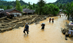 Des habitants progressent dans des eaux de crue au village de Tukka, en Indonésie, le 2 décembre 2025 ( AFP / YT HARIONO )