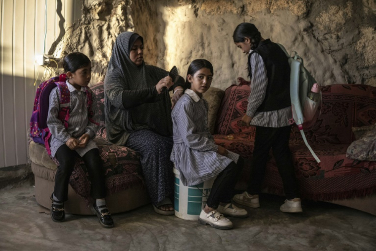 Arwa Amr coiffe sa fille Layan alors qu'elles se préparent pour l'école, à l'intérieur de la grotte que la famille a transformée en foyer dans le village d'Al-Tuwani, en Cisjordanie occupée par Israël, le 16 septembre 2026 ( AFP / John WESSELS )