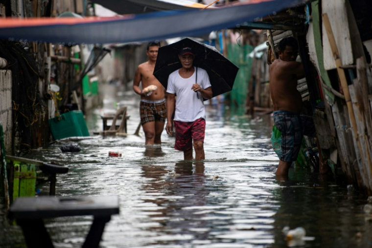 Des habitants dans une rue inondée de l'île de Pugad, dans la province de Bucalan, le 21 août 2025 aux Philippines ( AFP / Ted ALJIBE )