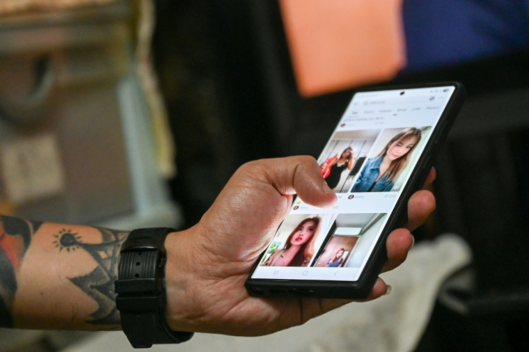 Delfard Tay regarde sur son téléphone des photos de sa fille Shermaine, avant son décès, le 18 septembre 2025 à Singapour ( AFP / Roslan RAHMAN )