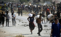 Des Palestiniens transportent des sacs d'aide humanitaire, dans le camp de Nousseirat, dans le centre de la bande de Gaza, le 27 juillet 2025 ( AFP / Eyad BABA )