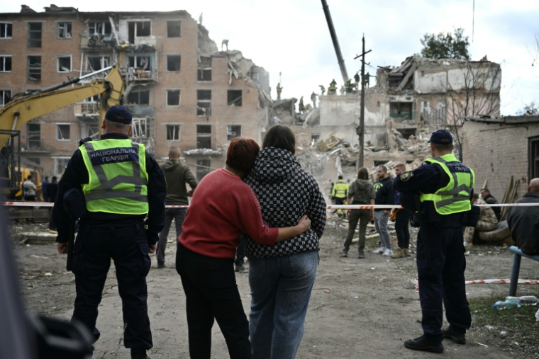 Des habitantes s'étreignent en regardant un immeuble résidentiel détruit par une frappe aérienne russe à Prylouky, le 7 octobre 2026 dans le nord de l'Ukraine ( AFP / Genya Savilov )