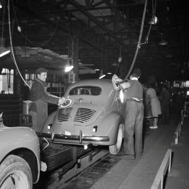 Des ouvriers polissent la carrosserie d'une 4CV sur la chaîne de montage de l'usine Renault, en avril 1950 sur l'île Seguin, à Boulogne-Billancourt, dans les Hauts-de-Seine ( AFP / Henri ELWING )