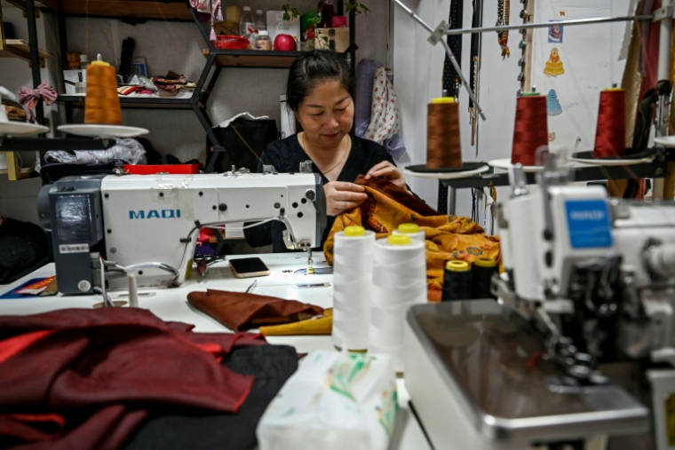 Une femme coud des vêtements dans le district de Keqiao, l'un des plus grands centres asiatiques du textile à Shaoxing, dans la province chinoise du Zhejiang, le 8 mai 2025 ( AFP / Greg Baker )