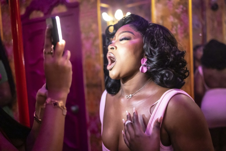 Une cliente pose pour une photo dans un espace selfie décoré à l'intérieur des toilettes du restaurant-bar Zaza à Lagos, le 23 août 2025. De la ville débridée de Lagos à la conservatrice Abuja, en passant par la conservatrice Kano, les Nigérianes prennent très au sérieux la dernière tendance : se prendre en photo dans les toilettes des restaurants et clubs branchés pour les partager sur les réseaux sociaux. Aujourd'hui, le culte du téléphone portable s'installe dans les toilettes, nouveaux temples du selfie.Les établissements ont compris l'enjeu : les nombreux influenceurs du pays le plus peuplé du continent ont le pouvoir, d'un simple « tag », de leur offrir une publicité gratuite à condition que la décoration les mette en valeur. ( AFP / OLYMPIA DE MAISMONT )