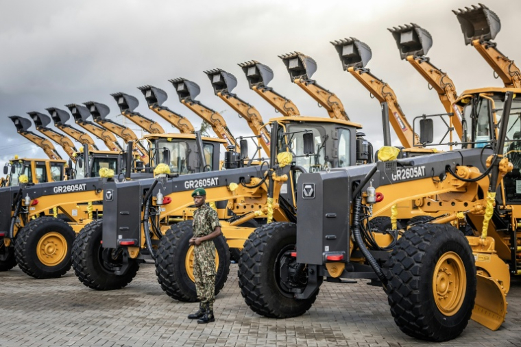 Un membre du Service national de la jeunesse (NYS) du Kenya surveille des excavatrices et autres machines lourdes stationnées avant une cérémonie d'inauguration d'une raffinerie au port de Lamu (Kenya), le 30 septembre 2026 ( AFP / Luis TATO )