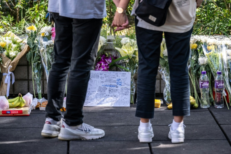 Des fleurs et des messages déposés devant le complexe résidentiel Wang Fuk Court ravagé par un incendie meurtrier, le 29 novembre 2025 à Hong Kong ( AFP / Philip FONG )