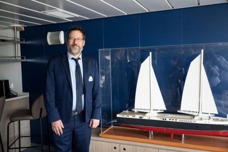 Le président de Neoline, Jean Zanuttini, à côté d'une maquette du Neoliner Origin, premier cargo à voile de nouvelle génération, au port de Marseille le 6 octobre 2025 ( AFP / Miguel MEDINA )