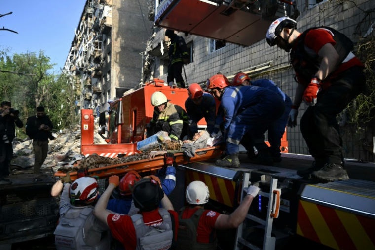 Des sauveteurs ukrainiens évacuent une personne blessée des décombres d'un immeuble résidentiel endommagé par une frappe de missiles russes, le 17 juin 2025 à Kiev ( AFP / Genya SAVILOV )