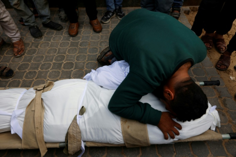 Un homme prosté sur le corps d'une personne tuée dans une frappe israélienne, à l'hôpital Al-Chifa le 4 février 2026 ( AFP / Omar AL-QATTAA )