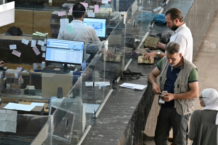 Des clients attendent aux guichets de la banque centrale de Damas, le 21 mai 2025 en Syrie ( AFP / LOUAI BESHARA )