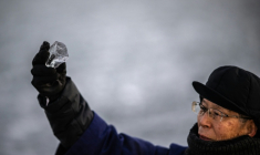 Kiyoshi Miyasaka, prêtre japonais du culte shinto, brandit un morceau de glace du lac Suwa, le 29 janvier 2026 dans la préfecture de Nagano, dans le centre de l'archipel  ( AFP / Philip FONG )