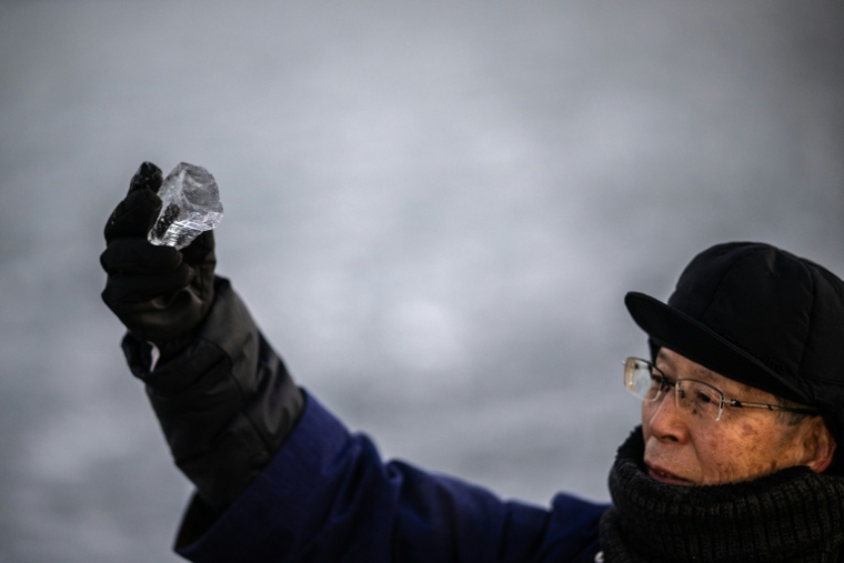 Kiyoshi Miyasaka, prêtre japonais du culte shinto, brandit un morceau de glace du lac Suwa, le 29 janvier 2026 dans la préfecture de Nagano, dans le centre de l'archipel  ( AFP / Philip FONG )