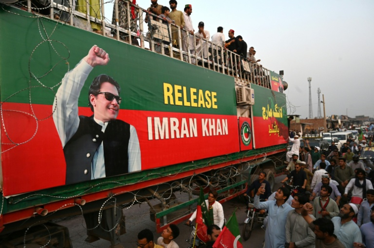 Sur et au pied d'un camion décoré, les partisans du parti PTI de l'ancien Premier ministre emprisonné Imran Khan participent à une marche dans le district de Khyber, dans la province pakistanaise du Khyber Pakhtunkhwa, le 7 octobre 2026 ( AFP / Abdul MAJEED )