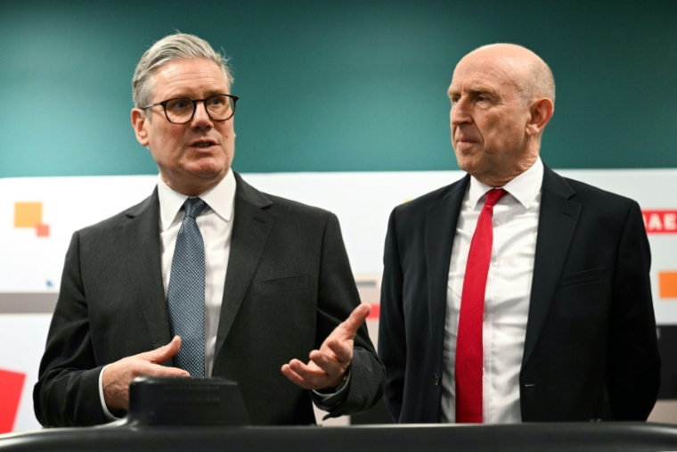 Le Premier ministre britannique Keir Starmer (à gauche) et le secrétaire à la Défense John Healey lors d'une rencontre avec des apprentis de l'entreprise aérospatiale BAE system, à Barrow-in-Furness, dans le nord-ouest de l'Angleterre, le 20 mars 2025 ( POOL / Oli SCARFF )