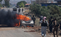 Des combattants bédouins et tribaux se déploient alors qu’une voiture est en feu à l’entrée ouest du bastion druze de Soueïda, dans le sud de la Syrie, le 18 juillet 2025 ( AFP / Bakr ALKASEM )