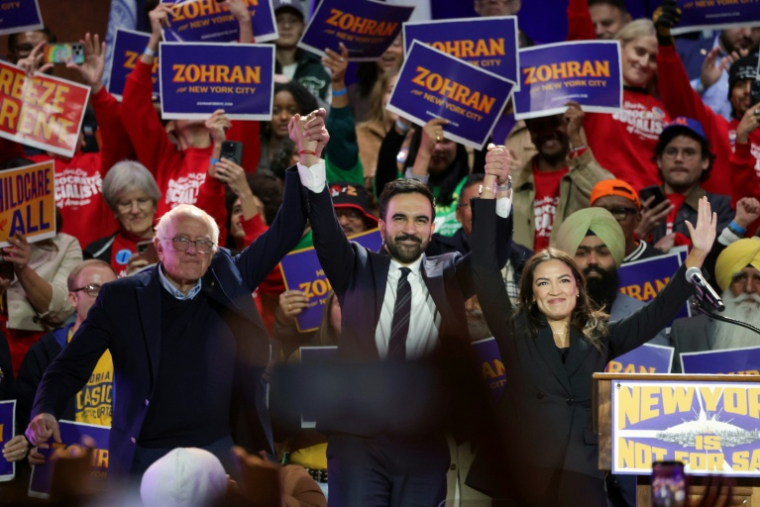 Le candidat démocrate à la mairie de New York Zohran Mamdani (centre), en meeting avec deux figures de la gauche américaine: le sénateur Bernie Sanders (gauche) et la représentante Alexandria Ocasio-Cortez (droite), au Forest Hills Stadium du Queens le 26 octobre 2025 ( AFP / ANGELA WEISS )