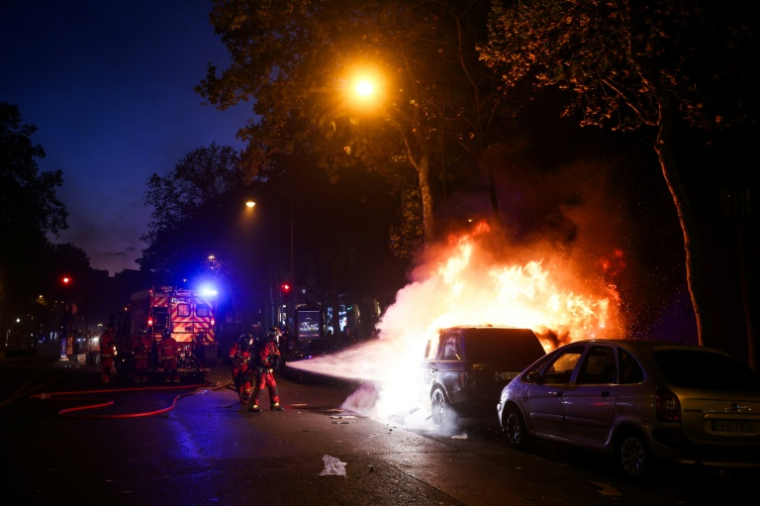 Les pompiers éteignent un véhicule en feu à Paris, lors de la manifestation contre la "vie chère", le 17 octobre 2026 ( AFP / Kiran RIDLEY )