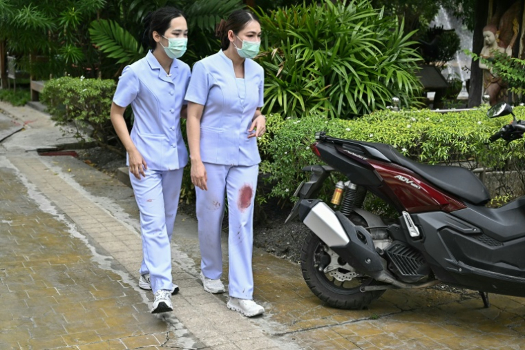 Des infirmières à l'uniforme tâché de sang, après la fusillade dans un lycée près de Bangkok, le 7 août 2026 ( AFP / Lillian SUWANRUMPHA )