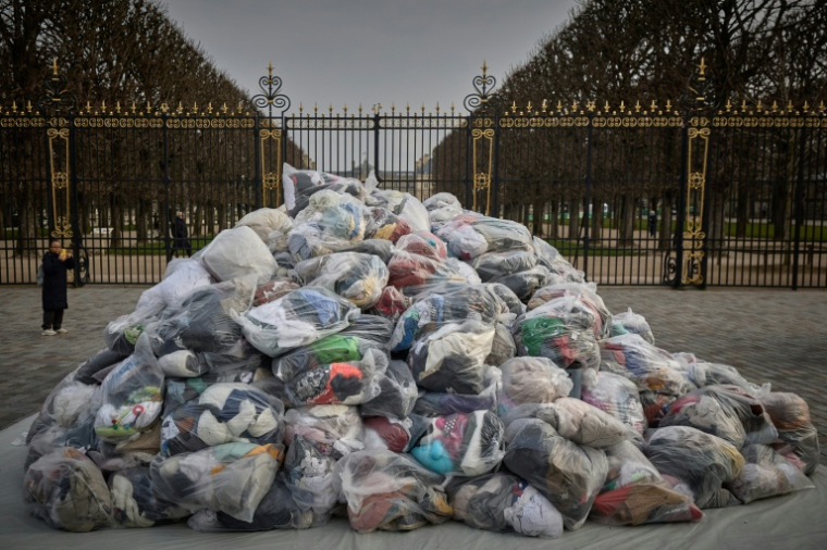Des sacs de déchets textiles devant la porte du Palais du Luxembourg, où se trouve le Sénat lors d'une manifestation contre la fast-fashion, à Paris, le 14 mars 2025 ( AFP / Kiran RIDLEY )