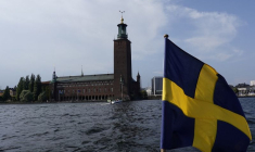 Le drapeau suédois flotte sur un bateau devant la Stadshuset de Stockholm