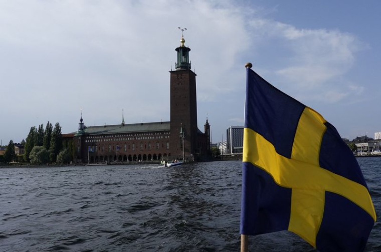 Le drapeau suédois flotte sur un bateau devant la Stadshuset de Stockholm