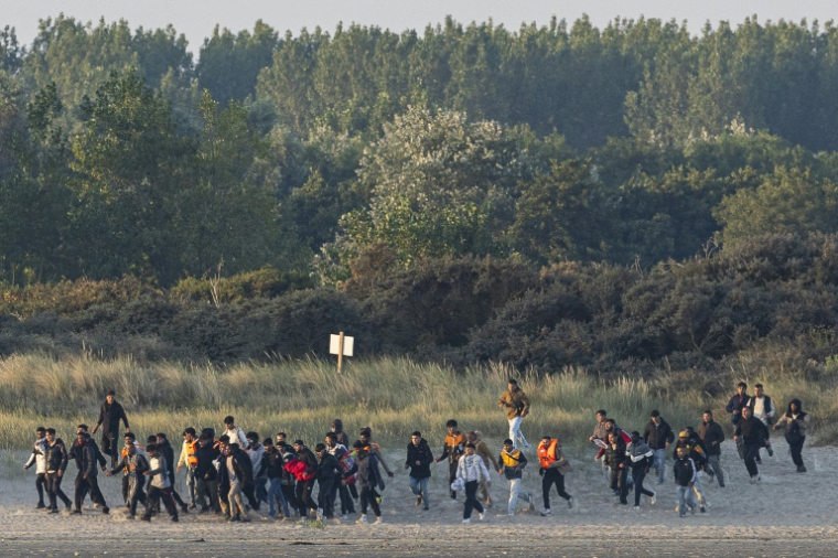 Des migrants courent sur la plage pour tenter d'embarquer à bord d'un "taxi-boat" pour traverser la Manche, le 11 août 2025 à Gravelines, dans le Nord ( AFP / Sameer Al-DOUMY )