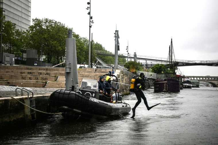 Un plongeur de la brigade fluviale saute dans la Seine depuis un bateau de patrouille à Paris, le 9 mai 2023 ( AFP / Christophe ARCHAMBAULT )