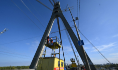 Des techniciens réparent une ligne électrique de trolleybus à proximité des dégâts constatés sur un pilier du pont, à la suite d’une attaque de drone contre le pont du Nord à Kiev, le 3 octobre 2026 ( AFP / Sergei SUPINSKY )