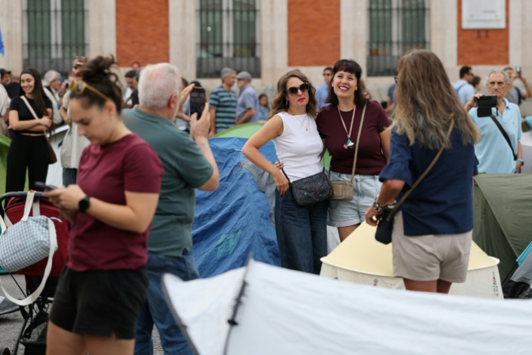 Des touristes prennent des photos parmi les tentes dressées par des manifestants qui protestent contre les expulsions et la crise du logement, le 27 septembre 2026 à Madrid ( AFP / Thomas COEX )